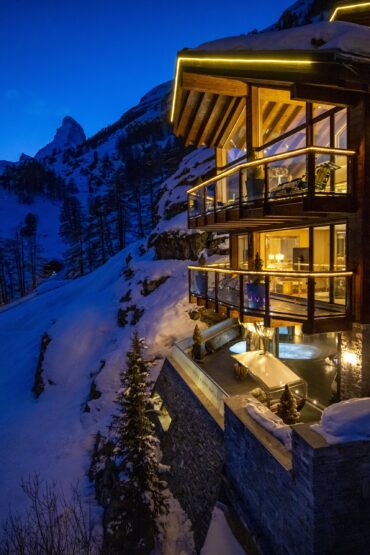 Chalet Zermatt peak at sunset lit up. With matterhorn in background. Part of the luxury chalet club collection