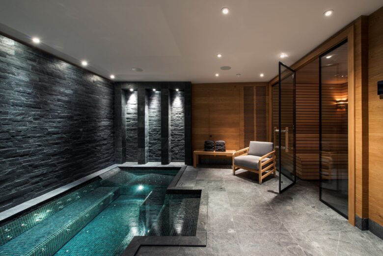 Indoor swimming pool with seating next to at Chalet Le Grenier in Meribel. Part of the luxury chalet club collection